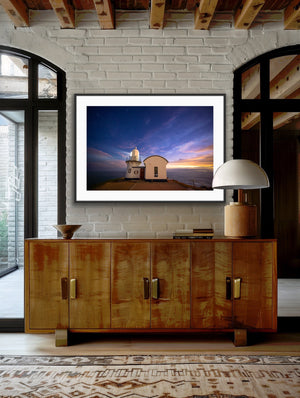Last Light framed against a white brick wall above a timber sideboard