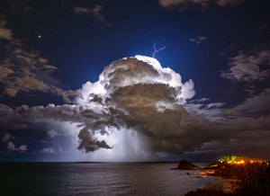 Storm over Nobby's — a lightning-lit storm cell offshore beneath a star-filled sky